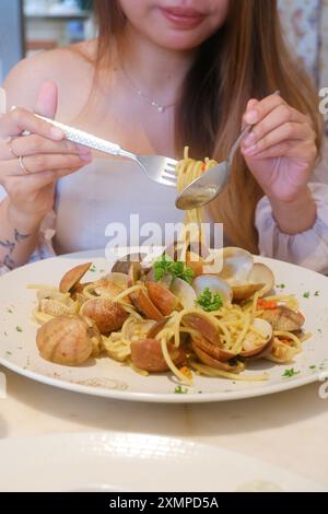 Ein hübsches Mädchen genießt eine Pasta mit Meeresfrüchten in einem schicken Restaurant. Stockfoto