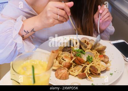 Ein hübsches Mädchen genießt eine Pasta mit Meeresfrüchten in einem schicken Restaurant. Stockfoto