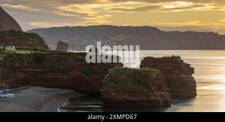 Sandsteinmeer stapeln sich in der Ladram Bay in Devon, mit Sidmouth in der Ferne, die bei Sonnenaufgang im Juli erfasst wurde. Stockfoto