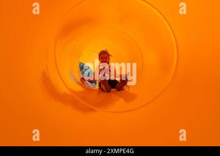 Kleines Mädchen, das Spaß in der Röhrentunnel Rutsche auf dem Spielplatz hat Stockfoto