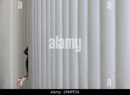 Wiesbaden, Deutschland. Juli 2024. Ein Jogger verschwindet zwischen den Säulen der Säulenhalle des Theaters, aufgenommen um 1838/39 (Aufnahme mit langsamerer Verschlusszeit). Vermerk: Arne Dedert/dpa/Alamy Live News Stockfoto