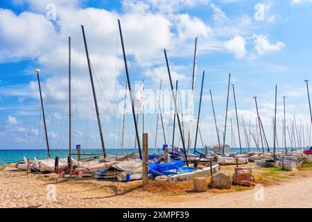 Tarragona, Spanien - 14. Juli 2024: Zahlreiche Segelboote ankern am Sandstrand von Tarragona, mit hohen Masten vor einem pulsierenden Himmel und tran Stockfoto