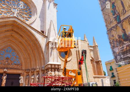 Tarragona, Spanien - 15. Juli 2024: Arbeiter an einem Aufzug, die Restaurierungsarbeiten an der Kathedrale von Tarragona durchführen, um die Mischung aus Erbe und Mode zu demonstrieren Stockfoto