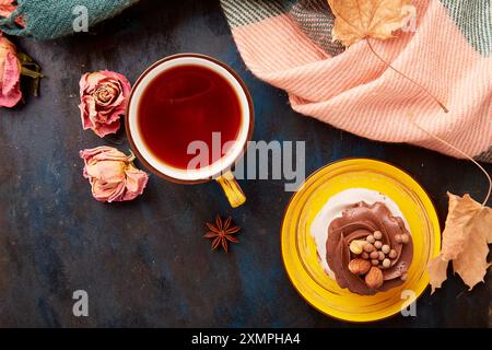 Ästhetischer Pavlova-Kuchen und Teetasse. Herbstästhetik Teezeit Vibes zwischen trockenen Rosen und Blättern. Einstellung des Herbsttisches. Stockfoto