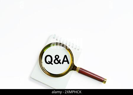 F & A Wort auf Holzblock mit Lupe. Weißer Hintergrund. Q und A auf weißem Papier mit Brille geschrieben. Finanzielle Fragen und Antworten werden beantwortet Stockfoto