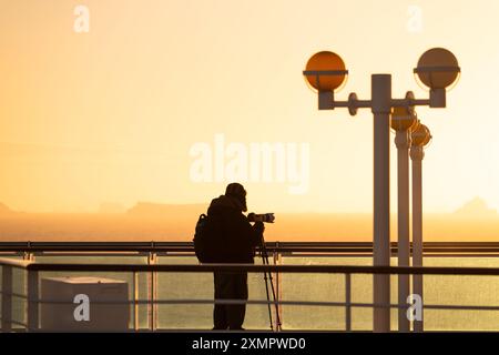 Sonnenuntergang Antarktis Kreuzfahrtschiff männlicher Passagier professioneller Fotograf in warmem Hut Teleobjektiv Kamerastativ warmes Sonnenlicht Magic Hour Stockfoto