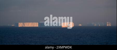 Antarktis Landschaft Landschaft schöne weite Ansicht große flache Eisberge Sonnenuntergang warmes Licht am Horizont Dunkelblaues Meer Stockfoto