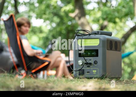 Tragbares Kraftwerk mit Lithium-Ferrophosphat-Batterie, das elektronische Geräte auflädt, die auf einem wilden Campingplatz verwendet werden. Stockfoto
