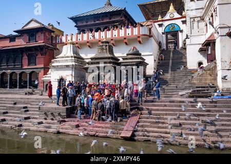 Familien versammeln sich, während ihre Toten entlang des heiligen Flusses Bagmati, Bhasmeshvar Ghat, Pashupatinath Hindutempel, Kathmandu, Nepal, verbrannt werden Stockfoto