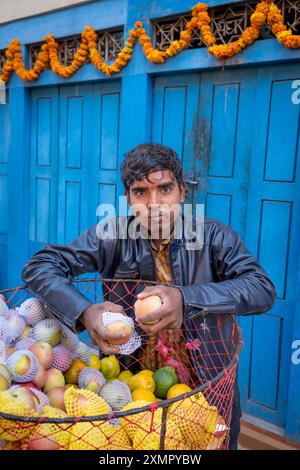 Ein junger Straßenverkäufer verkauft Obst von seinem Korb getakteten Fahrrad in den überfüllten Straßen von Kathmandu, Nepal Stockfoto