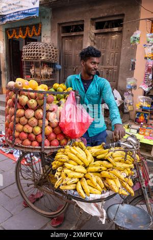 Ein junger Straßenverkäufer verkauft Obst von seinem Korb getakteten Fahrrad in den überfüllten Straßen von Kathmandu, Nepal Stockfoto