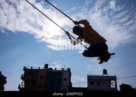 Der junge Mann schwingt auf Seil- und Bambusschaukel, die zeitweilig für das Diwali Festival of Lights im November in Panauti Town, Kathmandu, Nepal, eingerichtet wurden Stockfoto