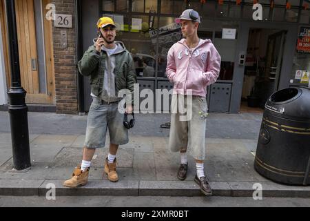 Ein paar trendige Anhänger der Mode standen auf dem Bürgersteig in der Nähe der Wardour Street, SOHO, London, Großbritannien Stockfoto