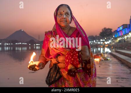 Eine Frau zündet eine Kerze am Puskar See während der Pushkar Kamel Fair in Pushkar, Rajasthan, Indien, Asien an Stockfoto