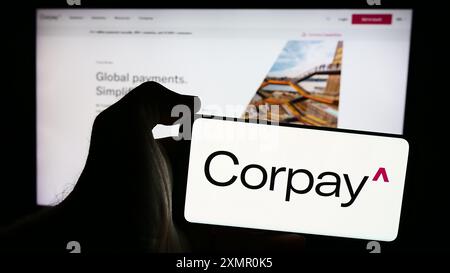 Person mit Smartphone und Logo des US-Zahlungsunternehmens Corpay Inc. Vor der Website. Schwerpunkt auf dem Display des Telefons. Stockfoto