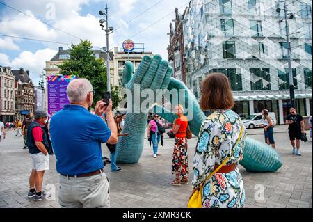 Amsterdam, Niederlande. Juli 2024. Eine Familie wird gesehen, wie sie Fotos an der Gedenkstätte macht. Drei Jahre nach der Ermordung des berühmten Kriminaljournalisten Peter R. de Vries steht ein Denkmal zu Ehren seines Andenkens im Zentrum von Amsterdam. Die Gedenkstätte, zwei bronzene helfende Hände, erinnert nicht nur an den Verbrechensreporter und seine Arbeit, sondern sorgt auch dafür, dass das "unmenschliche Verbrechen" seines Mordes nicht vergessen wird. Quelle: SOPA Images Limited/Alamy Live News Stockfoto