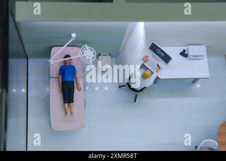 Patient liegt auf dem Untersuchungstisch neben dem am Computer arbeitenden Arzt. Übersichtssicht der ärztlichen Sprechstunde in der Klinik. Gesundheit und Diagnose Conce Stockfoto