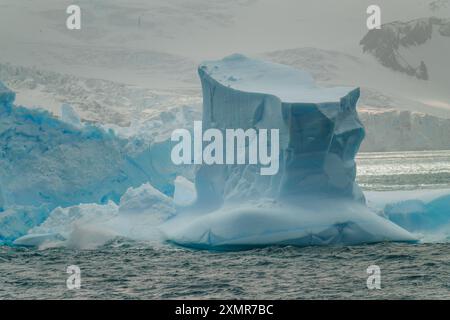 Unglaubliche Antarktis Blauer Eisberg im Ozean mit schneebedeckten Gletscherbergen im Hintergrund Elephant Island Stockfoto