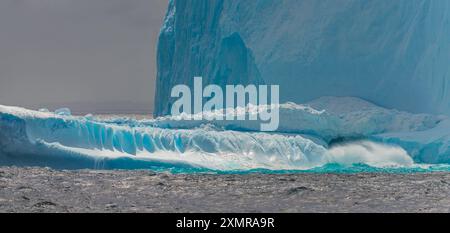 Antarktis Fine Art Photography Eisberg Wellen stürzen auf blauem Eis gegen graues Wasser und Himmel. Landschaftliche Szenenansicht Vom Schiff Aus Stockfoto