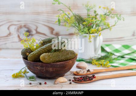 Schüssel mit leckeren eingelegten Gurken mit Gewürzen und Dill auf hellem Hintergrund. Marinierte hausgemachte eingelegte Gurken. Gesunde fermentierte Nahrung Stockfoto