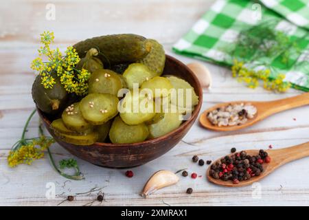 Schüssel mit leckeren eingelegten Gurken mit Gewürzen und Dill auf hellem Hintergrund. Marinierte hausgemachte eingelegte Gurken. Gesunde fermentierte Nahrung. Stockfoto