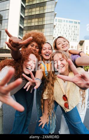 Vertikal. Eine Gruppe von Mädchen, die mit den Händen Gesten machen und in die Kamera schauen. Fünf junge Frauen lächeln. Teenager-Frauen lachen zusammen auf einem Meeting. F Stockfoto