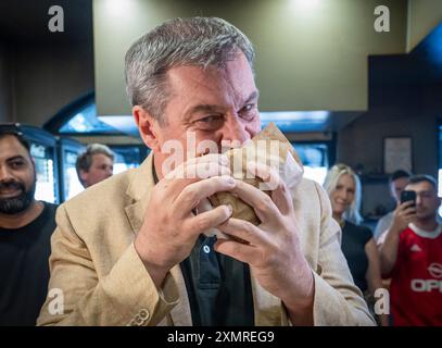 München, Deutschland. Juli 2024. Markus Söder (CSU), Ministerpräsident Bayerns, beißt in einem Dönerrestaurant einen frischen Döner. Söder hatte zuvor Kebabs an Instagram-Fans verlost. Quelle: Peter Kneffel/dpa/Alamy Live News Stockfoto