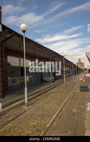 Verlassene Bahngleise im Victoria Dock (City Quay) in Dundee, Schottland, Großbritannien, mit historischem Lagerhaus im Hintergrund Stockfoto