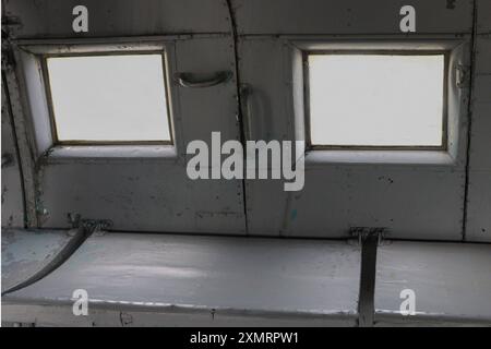Zwei quadratische Beleuchtungskörper, ein Sitz für Passagiere in einem alten, verlassenen Transportflugzeug. Stockfoto