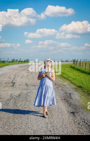 Glückliche reife Frau läuft an einem hellen Sommertag auf einer Landstraße. Stockfoto