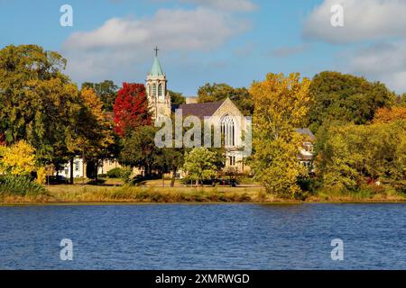 Herbstszene mit Blick über den Lake of the Isles in Richtung der 1925 Lake of the Isles Lutheran Church in Minneapolis, Minnesota. Die Kirche war designe Stockfoto