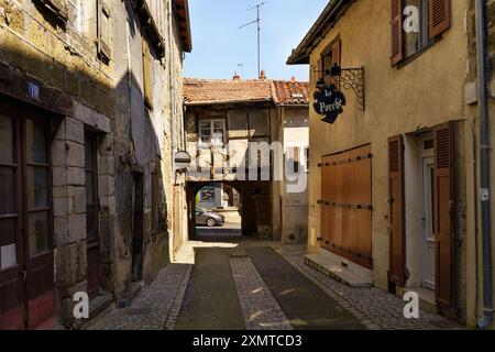 Langeac, Frankreich - 28. Mai 2023: Eine enge Steinallee in Langeac, Frankreich, mit einem Blick auf ein Auto, das durch ein Tor fährt. Die Gebäude sind alt A Stockfoto