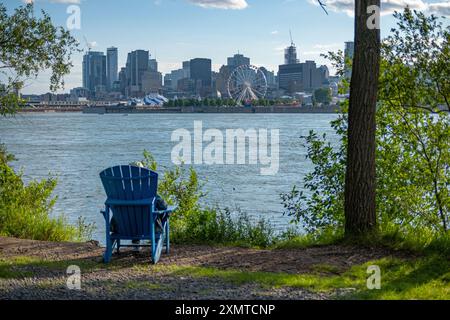 Blick auf Montreals Stadtmitte von St. Helen's Island mit einer nicht erkennbaren Person, die in einem blauen Gartenstuhl sitzt. An einem sonnigen Sommerende von After Stockfoto