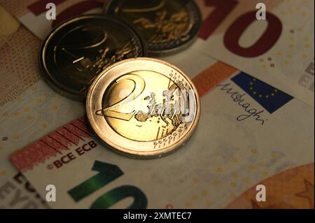 Glänzende neue 2-Euro-Münzen auf 10-Euro-Banknoten. Stockfoto