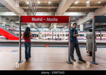 Der Bahnhof Madrid Atocha in Madrid, Spanien, zeigt Passagiere, die auf einen Pendlerzug in moderner Architektur warten. Stockfoto