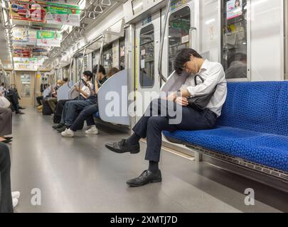 Nakano, Japan - 24. Mai 2024: Der Mann schläft im Metro Tokyo Train. Japan. Inemuri Stockfoto