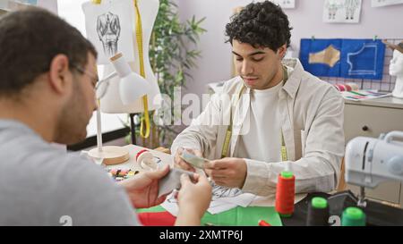 Zwei Schneiderinnen arbeiten in einem gut ausgestatteten Atelier zusammen, umgeben von Nähwerkzeugen und Stoffen. Stockfoto