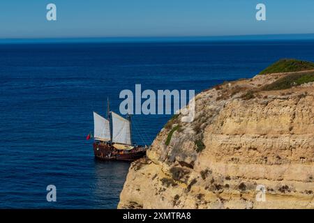 Küste, Höhlen von Benegil und Boot vom Seven Hanging Valleys Trail aus gesehen, Gemeinde Lagoa, Algarve, Portugal. Stockfoto