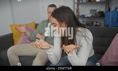 Eine Frau und ein Mann diskutieren in einem modernen Wohnzimmer und zeigen Emotionen von der Meinungsverschiedenheit eines Paares. Stockfoto