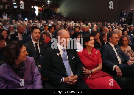 Austin Texas USA, 29. Juli 2024: LUCI BAINES JOHNSON (in rotem Kleid) und ihr Ehemann IAN TURPIN (links) sitzen in der ersten Reihe bei der Rede von Präsident Joe Biden in der LBJ Presidential Library zum 60. Jahrestag des Civil Rights Act. Luci Johnsons Vater, ehemaliger Pressesprecher Lyndon Baines Johnson, unterzeichnete die Akte 1964. Kredit: Pool/Bob Daemmrich Stockfoto