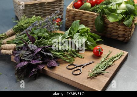 Verschiedene aromatische Kräuter, Gemüse und Scheren auf grauem Tisch, Nahaufnahme Stockfoto