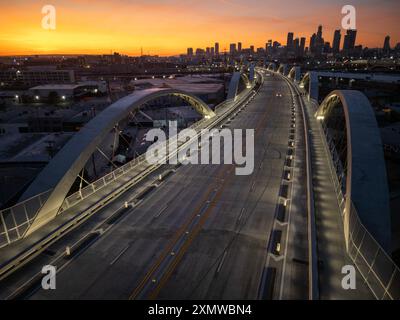 Blick bei Dämmerung auf die 6. Straße Viaduktbrücke über den Los Angeles River mit der Skyline der Innenstadt in der Ferne bei Sonnenuntergang Stockfoto