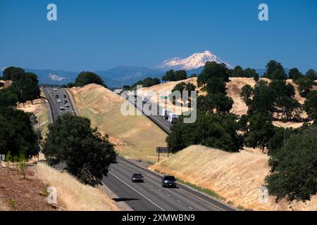 Blick auf Lkw und Verkehr, die entlang der interstate 5 im Tehama County Kalifornien fahren, mit dem dramatischen Kegel des Mount Shasta in der Ferne Stockfoto