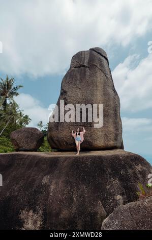 Eine Frau steht auf einem großen Felsen und blickt auf eine weitere massive Felsformation. Die Felsen sind bekannt als hin Ta hin Yai, eine beliebte Touristenattraktion o Stockfoto