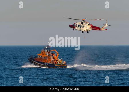 Weymouth, Dorset, Großbritannien. Juli 2024. Das Severn Class RNLI Lifeboat RNLB Ernest und Mabel bietet eine Abendvorstellung für die Öffentlichkeit vor der Küste in Nothe Gardens während des Wohltätigkeitstages während der Rettungsbootwoche in Weymouth in Dorset. Ein zusätzlicher Bonus für die Zuschauer war ein außerplanmäßiger Auftritt des Coastguard Helikopters von Lee on Solent, der ein Mitglied der Hubschraubercrew vom Rettungsboot-Deck aus holte, nachdem er in das Gebiet gerufen wurde, um die Küste von Portland zu durchsuchen. Bildnachweis: Graham Hunt/Alamy Live News Stockfoto