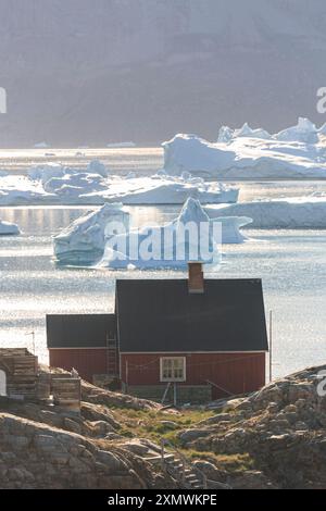 Typisch grönländische Häuser vor Eisbergen und Bergen, sonnig, Sommer, Uummannaq, Grönland Stockfoto