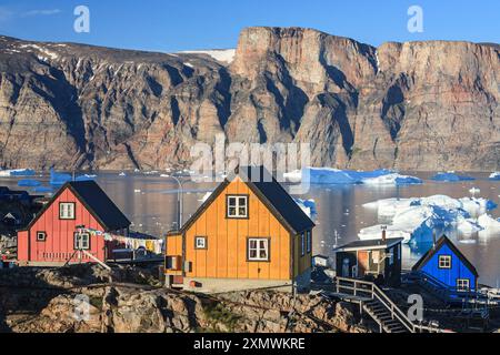 Typisch grönländische Häuser vor Eisbergen und Bergen, sonnig, Sommer, Uummannaq, Grönland Stockfoto