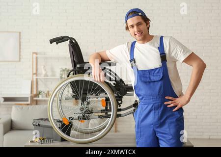 Männlicher Arbeiter repariert Rollstuhl im Zimmer Stockfoto