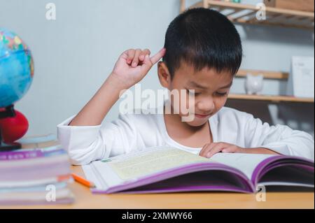 Bildungskonzept, trauriger müder, frustrierter Junge, der mit vielen Büchern am Tisch sitzt, gelangweilter und müder Junge, der auf dem Schreibtisch in seinem Zimmer Hausaufgaben macht, Dif lernt Stockfoto