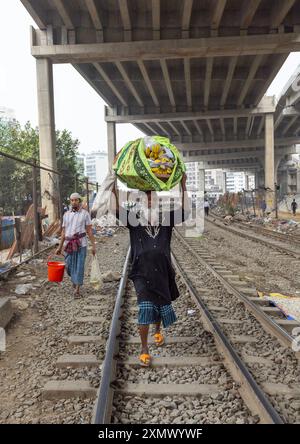 Ein alter Mann aus bangladesch läuft mit einer Tasche auf dem Kopf entlang der Schiene, Dhaka Division, Dhaka, Bangladesch Stockfoto